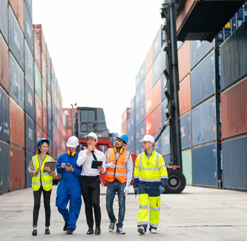 group-of-professional-engineer-worker-or-technici-2025-03-05-18-36-49-utc Group of professional engineer, worker or technician walk and discuss together about work in cargo container workplace area with crane and stack of container tank on background.